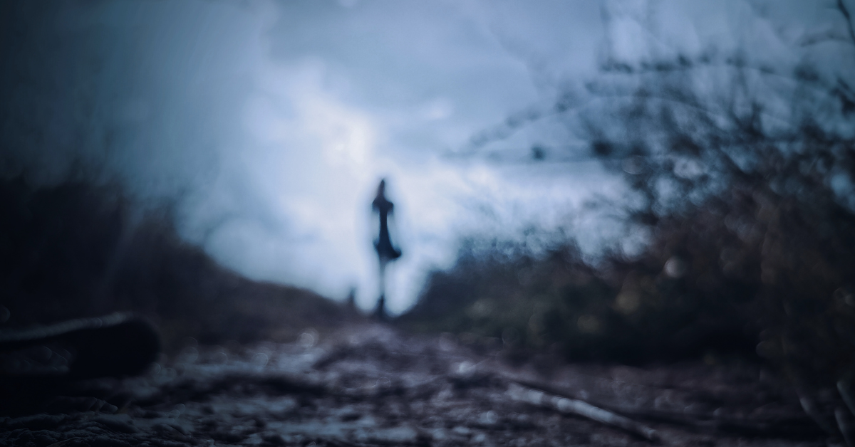 Dreary out of focus silhouette of a woman walking down a dirt path
